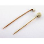 Two 19th century pearl-set stick pins, both pearls untested, the larger 9.2 x 7.8mm, mounted on gold