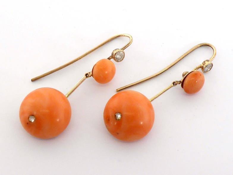 A pair of coral and diamond earrings, each large circular coral drop inset with a small rose cut,