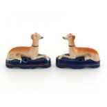 A pair of Staffordshire greyhounds seated on cushions to form pen holders. In very good condition,