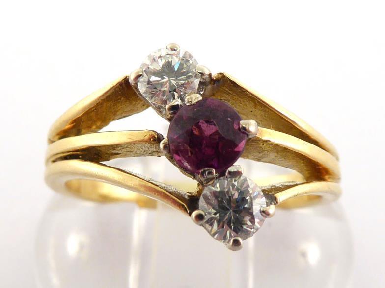 A garnet and diamond ring, the central round cut almandine obliquely set either side with two