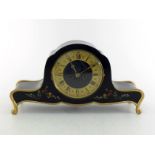 A mantel clock of "Napoleon Hat" form but shaped and gilt on scroll feet, the case black lacquered