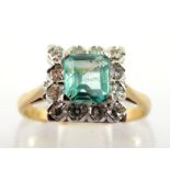 An emerald and diamond cluster ring, the central emerald cut stone 5.2 x 5.7mm, in a surround of