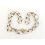 A moonstone necklace, composed of graduated oval cabochons, each spectacle set, to a bolt ring