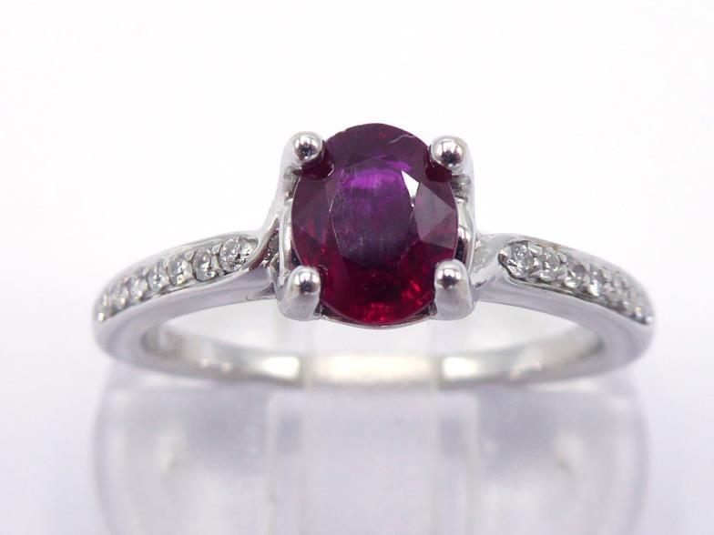 A ruby and diamond ring, the central oval cut stone approx. 0.77 carat (6 x 5 x 3mm), claw set above