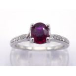 A ruby and diamond ring, the central oval cut stone approx. 0.77 carat (6 x 5 x 3mm), claw set above