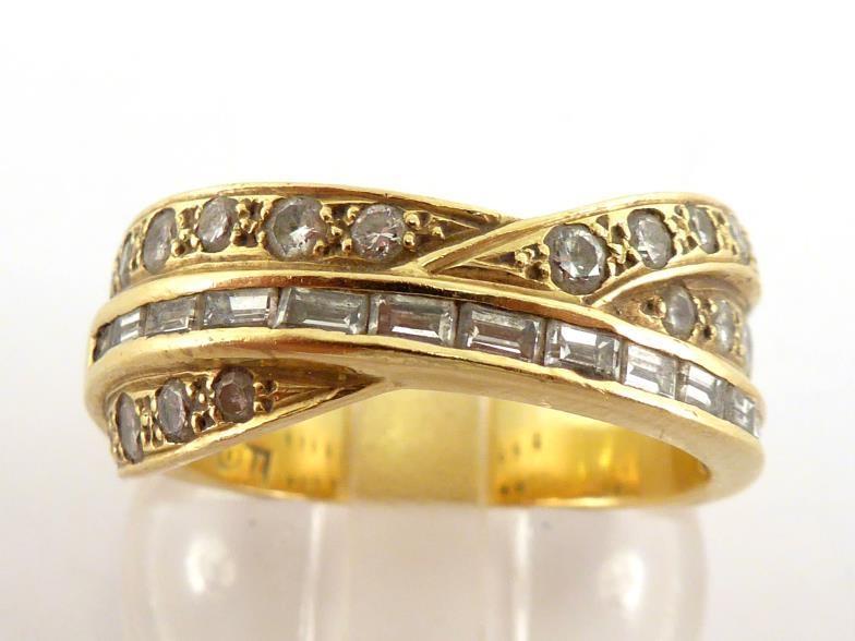 A diamond band ring, the three strand cross over bezel set with two bands of pave set brilliants,