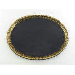 A large oval Victorian papier mache tray with raised rolled edge, the border with gilt decoration.