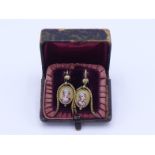 A pair of Victorian gold earrings, each drop with a cut out painted enamel of a lady dressed in