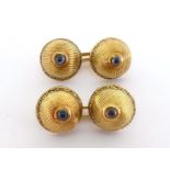 A pair of 18 carat gold and sapphire cufflinks, the textured domes each set with a small cabochon