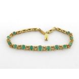 An emerald line bracelet, composed of graduated oval cut stones, the largest 5.2 x 4mm, mounted in