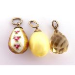 Three early 20th century Russian egg charms, the first with white body enamel and painted with