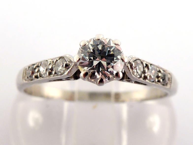 A diamond ring, the central brilliant approx. 0.34 carat, claw set above diamond set shoulders,