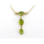 A 14 carat gold and tourmaline necklace, the drop composed of three spectacle set green oval