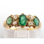 An emerald and diamond ring, composed of three graduated oval cut emeralds, the largest 4.8 x 2.5mm,