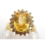 A yellow sapphire and diamond cluster ring, the central oval cut sapphire 9 x 7mm, in a surround