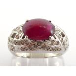 A ruby and diamond dress ring, the ruby cabochon 10.5 x 7.8mm, claw set above a domed brilliant