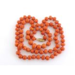 A vintage coral bead necklace, composed of uniform barrel shaped beads, individually knotted, to a