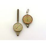 Two rolling wheel map measurers, each with multiple scales on two dials, one with ribbed handle, one