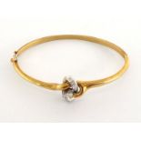 An 18 carat gold and diamond bangle, the central knot motif pave set with single cuts, a small