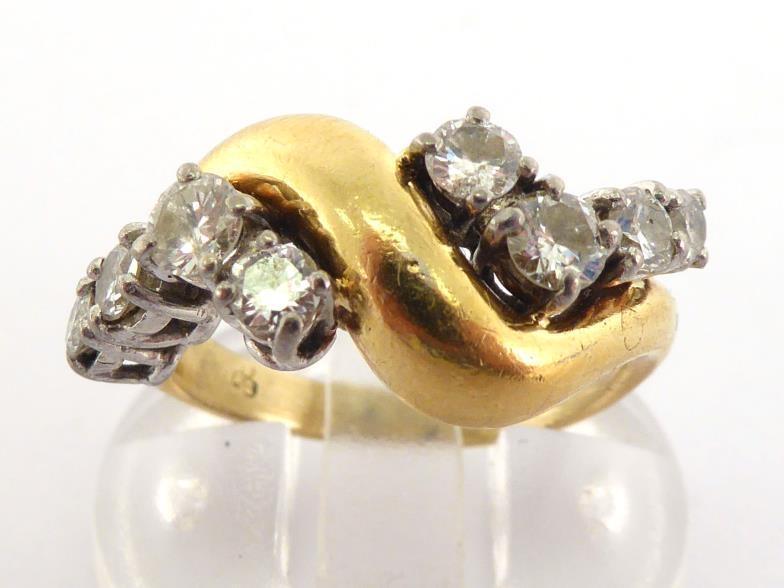 An 18 carat gold and diamond dress ring, the undulating bezel set either side with graduated