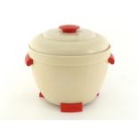 A 1960s ice bucket in cream with red handles and feet.