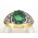 An 18 carat gold, emerald and diamond ring, the central round cut stone 7.2 x 4.5mm, claw set