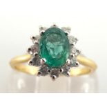 An emerald and diamond cluster ring, the central oval cut emerald 7 x 5mm, in a surround of small