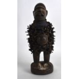 AN AFRICAN CARVED WOOD TRIBAL FETISH FIGURE standing upon a circular base. 11.25ins high.