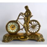 AN UNUSUAL NOVELTY EDWARDIAN BRASS MANTEL CLOCK in the form of a male standing beside his bicycle.