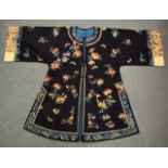 AN EARLY 20TH CENTURY CHINESE DARK BLUE SILKWORK JACKET decorated with extensive foliage and