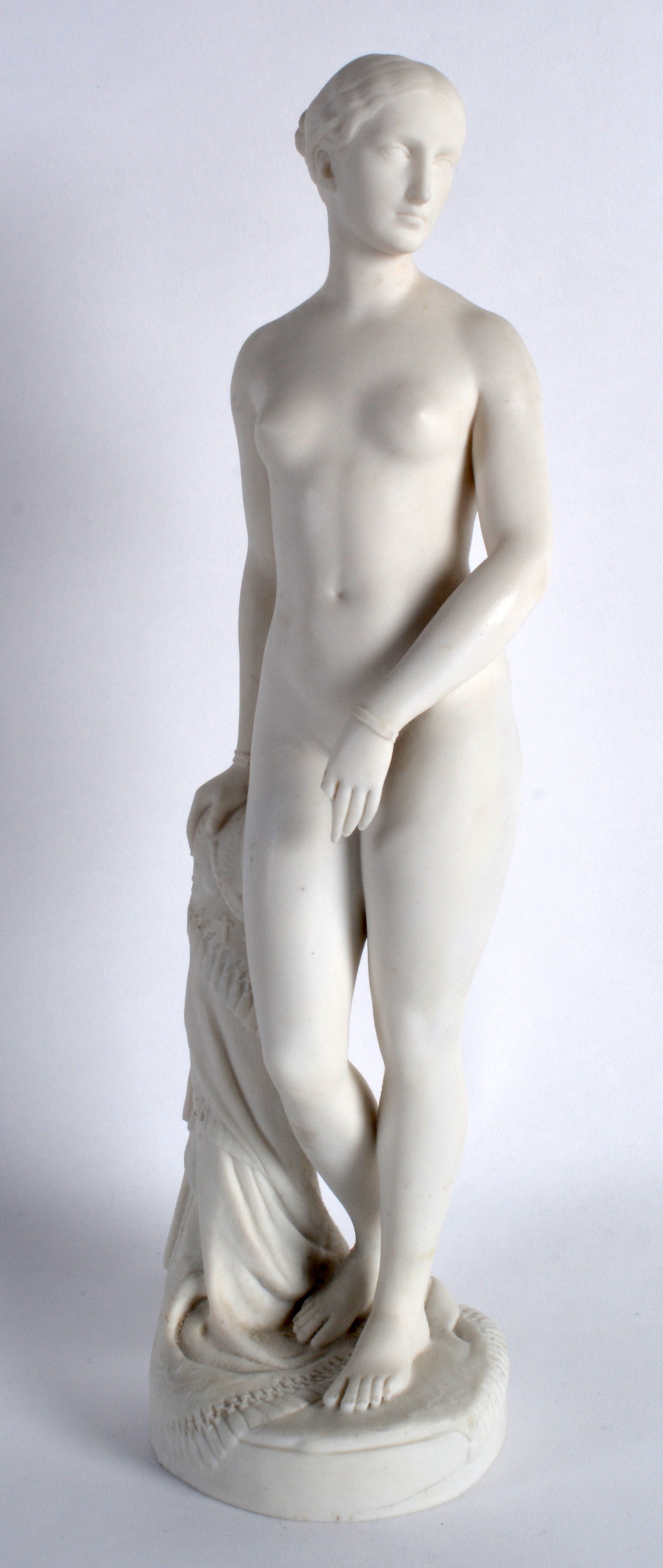 A MINTON PARIANWARE FIGURE OF A STANDING CLASSICAL NUDE FEMALE modelled with her hand resting upon a