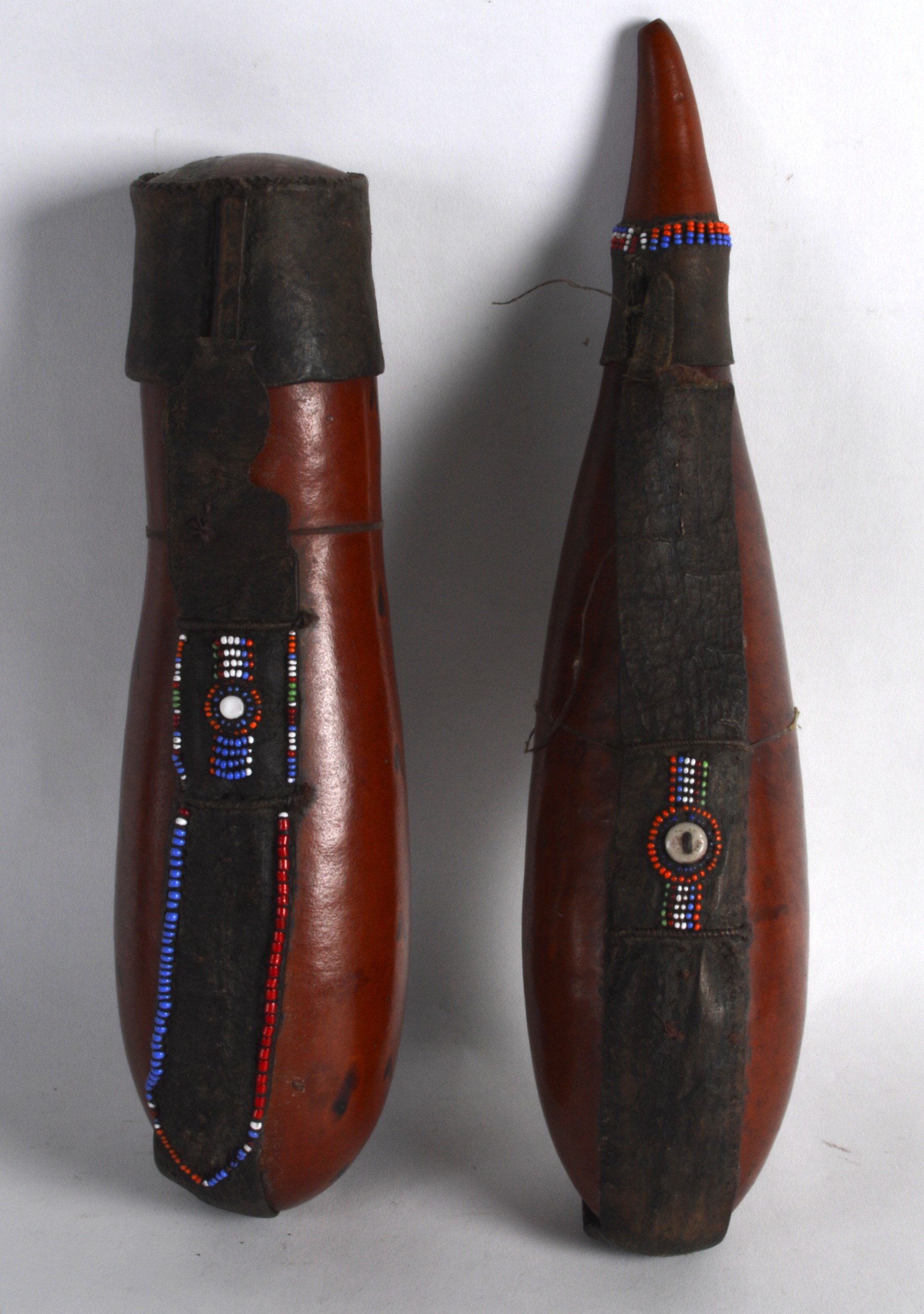 TWO LEATHER BOUND AFRICAN MASI BEADED GOURDS. 11.5ins long.