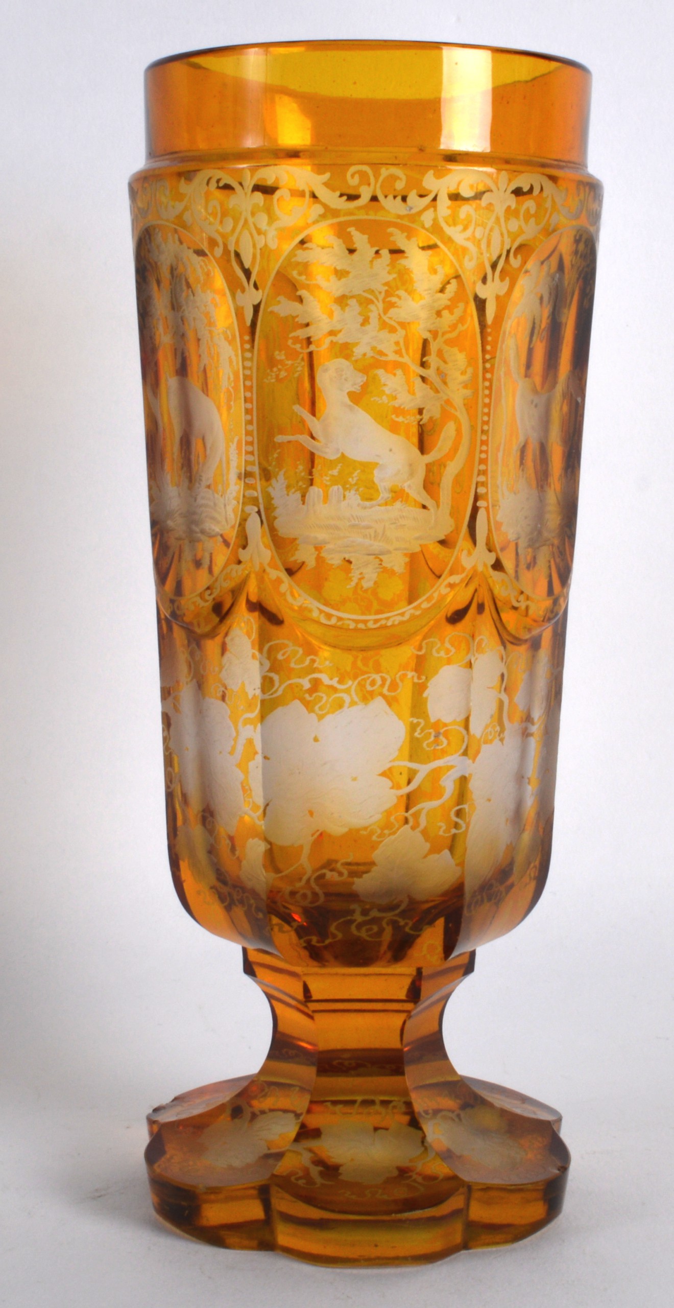 A 19TH CENTURY BOHEMIAN AMBER GLASS GOBLET decorated with horse, stags and acorn leaves. 8.25ins