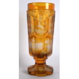 A 19TH CENTURY BOHEMIAN AMBER GLASS GOBLET decorated with horse, stags and acorn leaves. 8.25ins