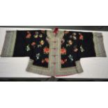 AN EARLY 20TH CENTURY CHINESE BLACK SILKWORK ROBE with brightly coloured borders, decorated with
