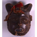 AN AFRICAN POLYCHROMED WOODEN MASK HEAD with material headware. 8.75ins long.