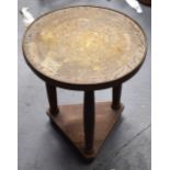 AN EARLY 20TH CENTURY ISLAMIC BRASS OCCASIONAL TABLE engraved with motifs, upon a triangular base.