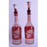 A MATCHED PAIR OF BOHEMIAN RUBY GLASS DECANTERS AND STOPPERS decorated with vine leaves. 37 cm &