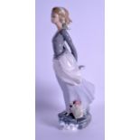 A LLADRO FIGURE OF A STANDING FEMALE modelled with her hands behind her back, upon a naturalistic