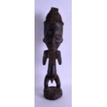 AN EARLY 20TH CENTURY AFRICAN CARVED TRIBAL FERTILITY FIGURE modelled as a male clutching his beard.