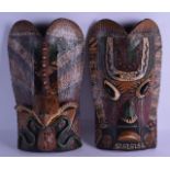 A PAIR OF SOUTH AMERICAN CARVED AND PAINTED WOODEN MASKS decorated with serpents. 40 cm x 22 cm.