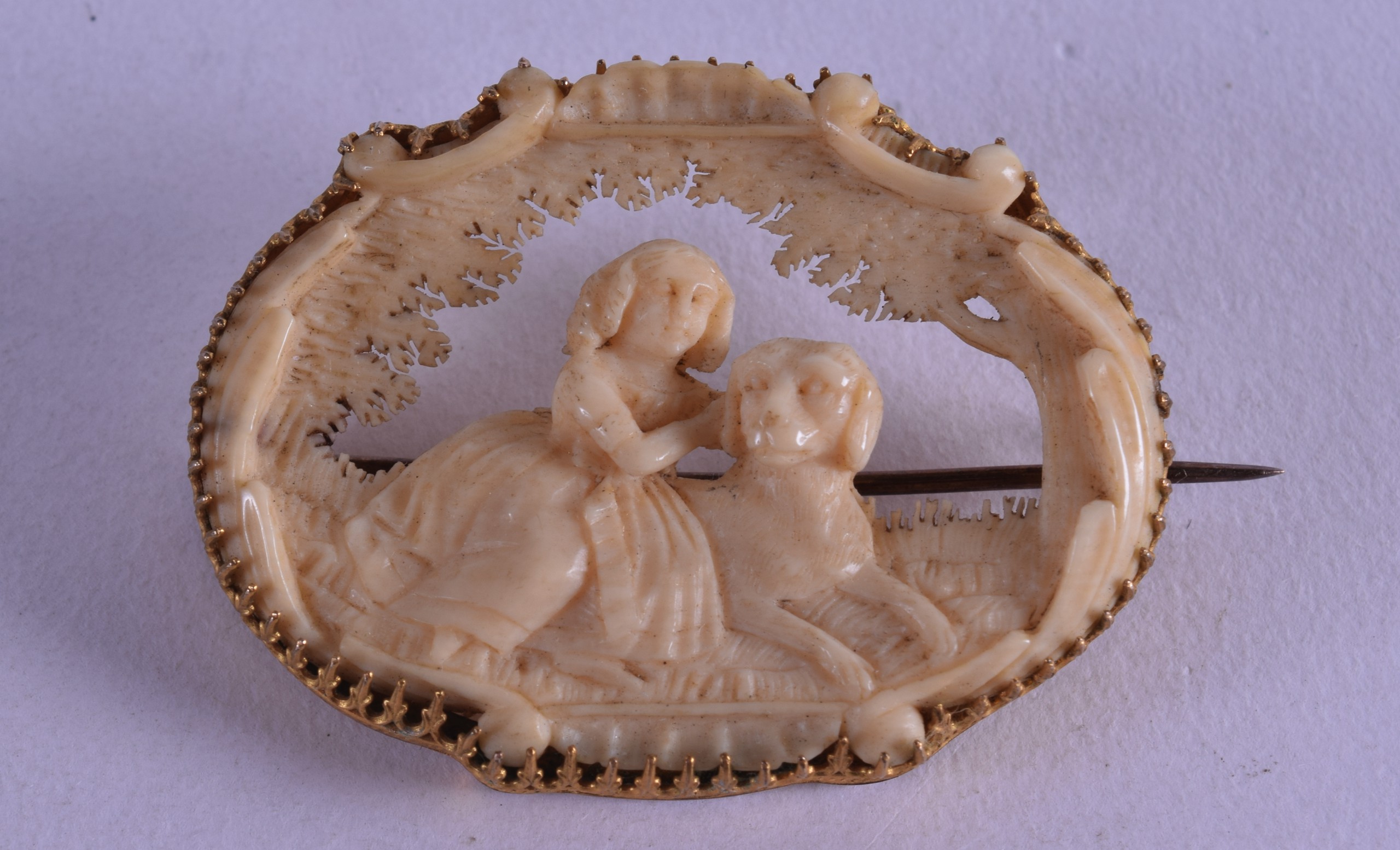 A FINE ANTIQUE CARVED IVORY BAVARIAN BROOCH decorated with a female and a hound. 4.25 cm wide.