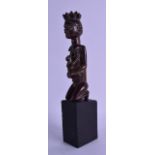 AN AFRICAN CARVED HARDWOOD FERTILITY FIGURE modelled as a mother and child, upon an ebonised base.