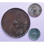 A GROUP OF THREE EARLY CHINESE BRONZE MIRRORS of various sizes. Largest 20 cm diameter. (3)