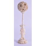 A 19TH CENTURY CHINESE CANTON CARVED IVORY PUZZLE BALL ON STAND modelled as an immortal standing