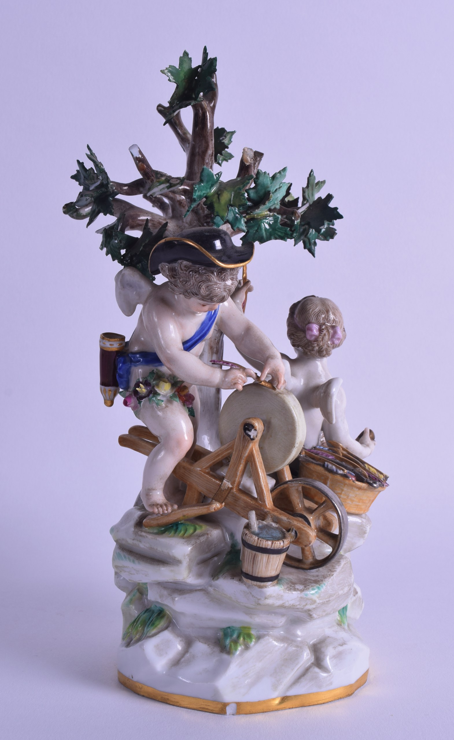 A 19TH CENTURY MEISSEN PORCELAIN FIGURE OF A KNIFE GRINDER modelled beside a putti, upon a