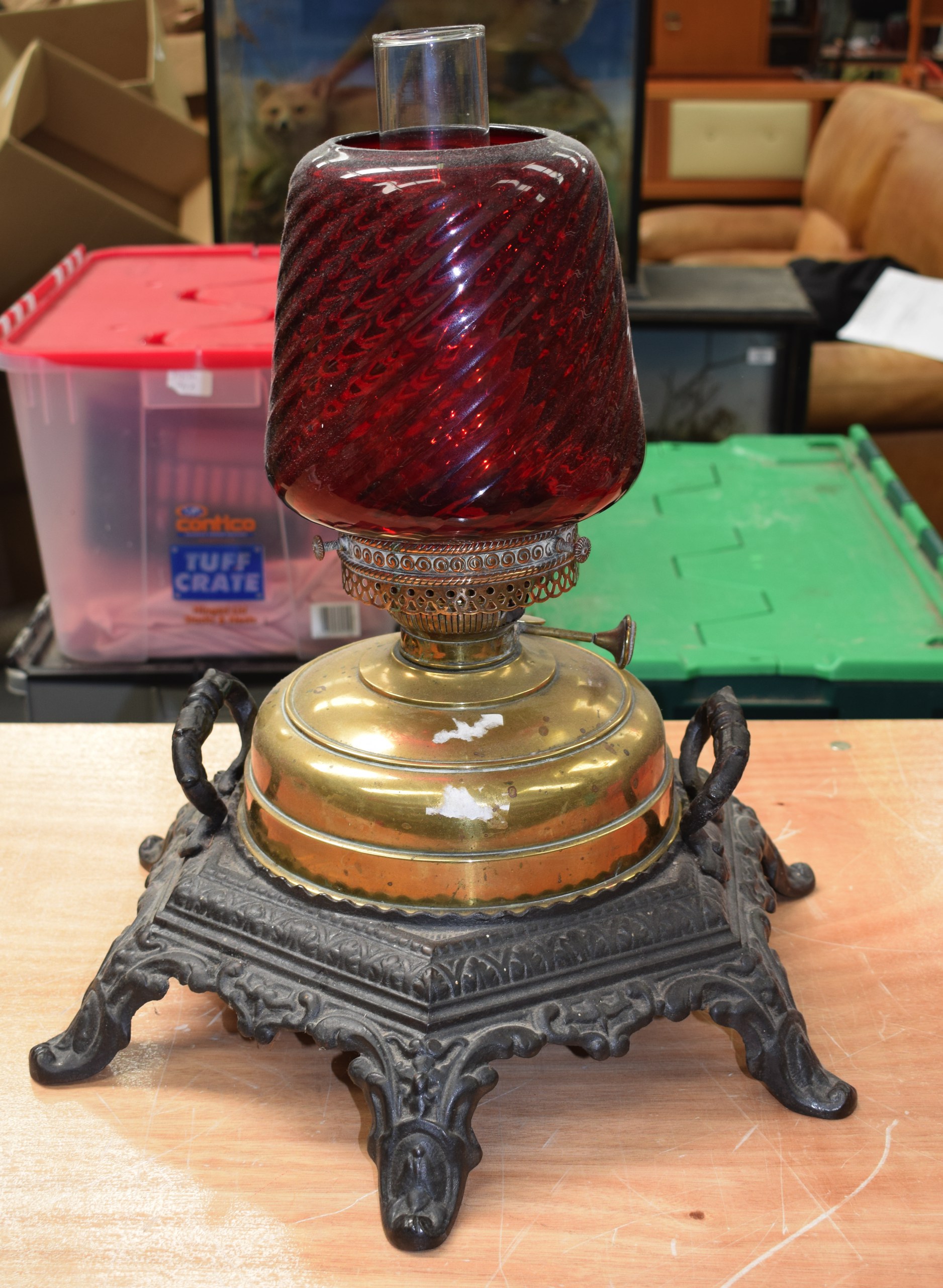 A VICTORIAN CAST IRON AND RUBY GLASS OIL LAMP.