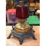 A VICTORIAN CAST IRON AND RUBY GLASS OIL LAMP.