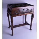 AN EARLY 20TH CENTURY CHINESE CARVED HARDWOOD CASKET ON STAND decorated with a roaming figures
