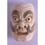 A 19TH CENTURY JAPANESE MEIJI PERIOD CARVED IVORY NOH MASK modelled as a scowling male with side